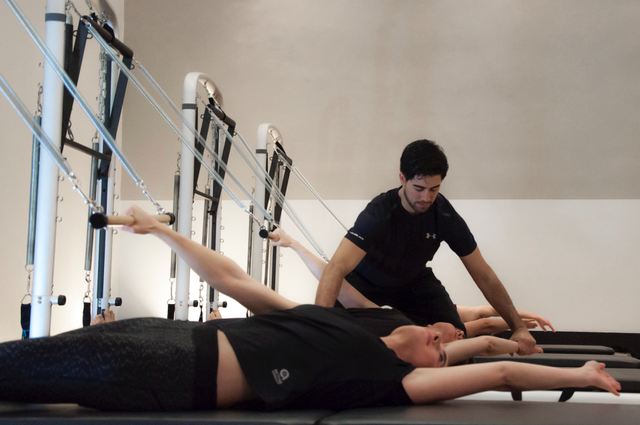Instructor guiando a una alumna en el Reformer